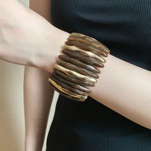 Close-up of a stylish amber marbled acrylic and gold-toned metal spliced bracelet