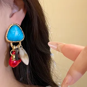 Primer plano de pendientes triangulares vintage con flecos de concha de colores en oreja