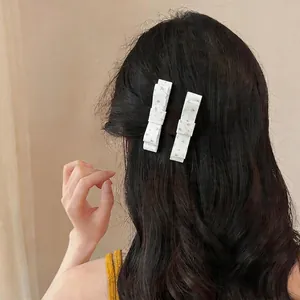 Elegant white floral fabric bow hair clips on dark wavy hair for back view styling