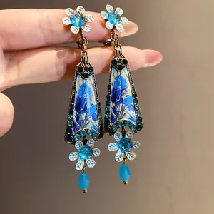 Close-up detail of vintage-style flower drop earrings with blue resin pattern and crystals