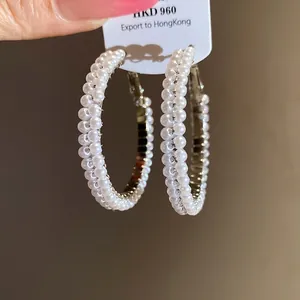 Detailed macro shot of elegant hoop earrings adorned with double rows of small white pearls