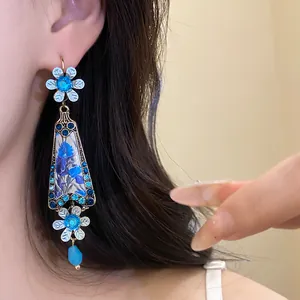 Detail of vintage flower drop earring with blue rhinestones and floral resin panel