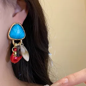 Detalle de pendientes vintage de triángulo turquesa con borlas de perlas y conchas
