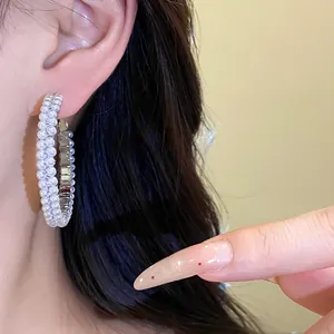 Close-up of elegant pearl hoop earrings on ear showing intricate bead details and shine