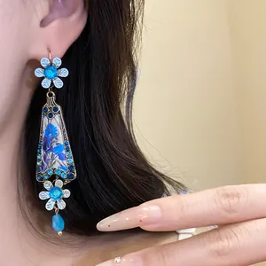 Close-up of vintage-style blue resin flower earring with rhinestones on model.