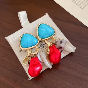 Pendientes vintage con borlas, cuentas rojas y turquesas sobre bolsa de joyería