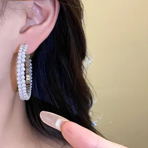 Elegant double-row pearl hoop earrings shown worn on a model's ear for close-up detail.