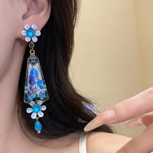 Detailed view of vintage flower drop earrings featuring blue rhinestones and floral resin.