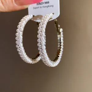 Macro view of detailed pearl hoop earrings showing an elegant white pearl texture