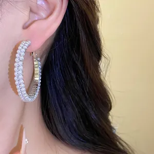 Detailed macro view of an elegant pearl-encrusted silver hoop earring worn on a model ear