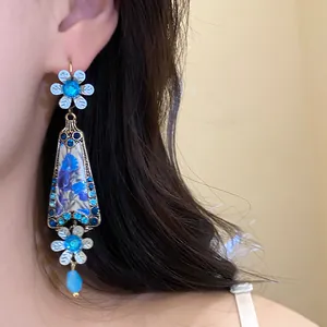 Detailed close-up view of vintage floral drop earrings with blue rhinestones and gold finish