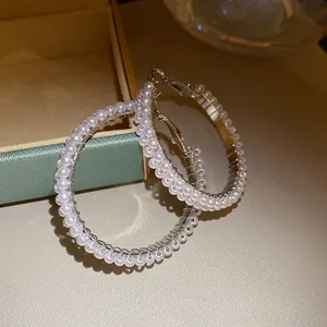 Close-up detail of elegant silver hoop earrings wrapped with delicate white pearls