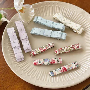 Detailed collection of assorted floral print fabric bow hair clips on a beige ceramic plate