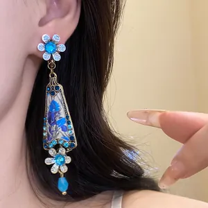 Close-up of vintage flower pendant earring with blue rhinestones worn by a model