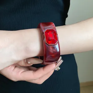 Detailed view of a vintage red marbled resin bangle with a large red crystal on wrist