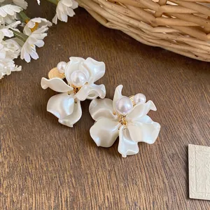 Elegante Perlen-Blütenblatt-Clip-Ohrringe mit floralem Design auf Holzgrund