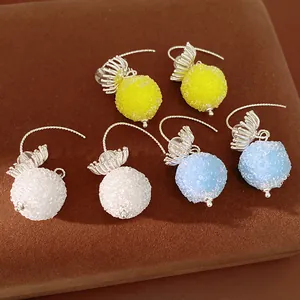 Close-up of frosted glass ball drop earrings in yellow, white, and blue colors.
