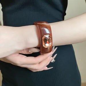 Detail of chunky brown resin square bangle featuring a large amber gemstone inlay