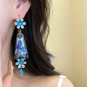 Detailed view of vintage blue floral resin dangle earrings with rhinestones on model