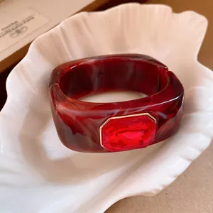 Close-up detail of a red faceted crystal set on a marbled burgundy resin square bangle