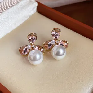 Close-up of 18k gold-plated flower earrings with pink crystals and pearls.