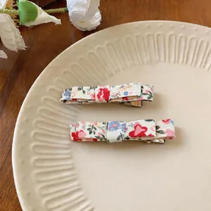 Detailed view of two elegant floral print fabric bow hair clips on a vintage ceramic plate