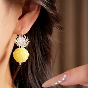 Close-up detail of sweet glass flower earrings with a textured yellow round bead