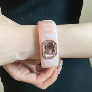 Close-up of luxury pink marble resin square bangle with faceted gemstone on wrist