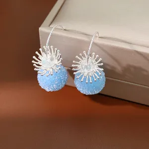 Detailed view of elegant light blue frosted bead earrings with silver sunburst decorative caps