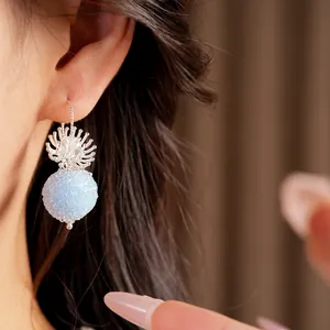 Close-up of elegant light blue frosted bead earrings featuring a silver flower design.