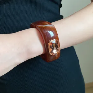 Close-up of amber marbled resin square bracelet with a large champagne rhinestone.