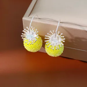 Close-up detail of yellow beaded glass ball earrings featuring silver flower hook design