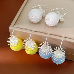 Close-up of elegant glass beaded flower drop earrings in white, yellow, and blue.