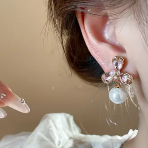 Close-up detail of vintage flower stud earrings with pink crystal and pearl drop charm