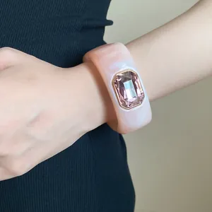 Close-up of a stylish marbled resin bangle featuring a large pink faceted crystal gemstone.