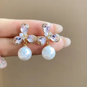 Close-up of elegant flower pearl earrings with pink crystals and 18k gold plating.