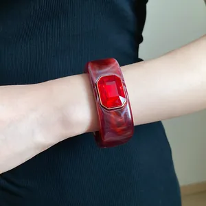 Close-up of dark red marbled resin bangle with large red emerald-cut gemstone detail.