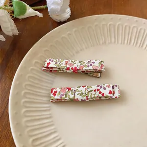 Detailed close-up view of elegant floral print fabric bow hair clips on a ceramic plate.