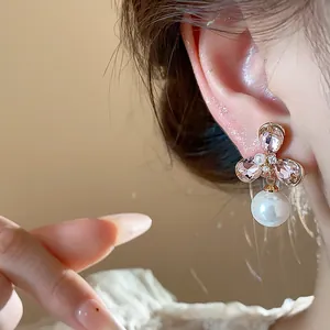 Detailed macro view of French vintage 18k gold plated floral earrings featuring a pearl drop.