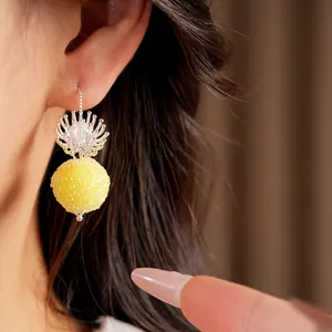 Macro close-up of elegant yellow glass bead earrings with silver flower detail on model