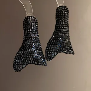 Primo piano di orecchini geometrici irregolari con strass neri incastonati.
