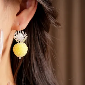 Macro detail showing a sweet yellow frosted ball earring with elegant silver flower hook