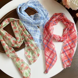 High-angle view of lightweight floral and plaid silk scarves on a white table with tray