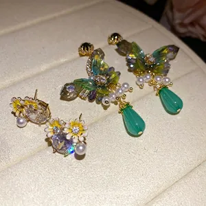 Elegant forest style butterfly and floral zircon earrings with pearls on a jewelry tray.