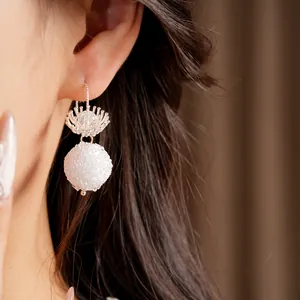 Close-up detail of minimalist glass flower earrings with an elegant frosted bead drop