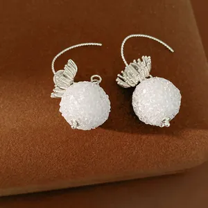 Close-up of elegant silver hook earrings with white frosted crystal glass balls