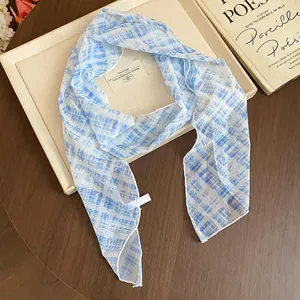 Close-up detail of a blue and white checkered floral silk scarf with an elegant drape.