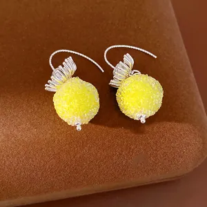 Detailed close-up of sweet yellow round beaded earrings with silver petal-shaped hooks
