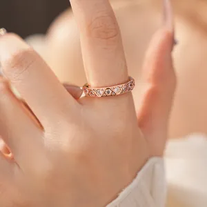 Detailed view of a rose gold geometric ring with triangular zircon patterns on finger