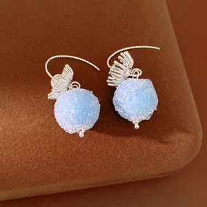 Close-up of elegant light blue frosted glass ball earrings with silver floral hook detail